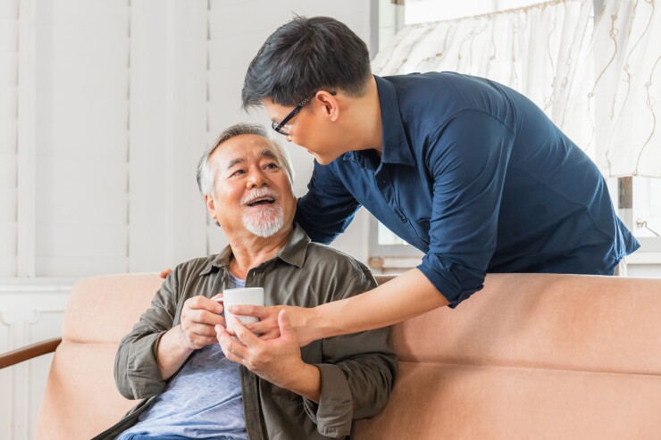 Younger man, son, giving father a cup of tea