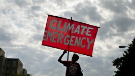 A protester holds a sign that reads "Climate Emergency" while blocking an intersection during the Shut Down DC climate demonstration in Washington Sept. 23, 2019.