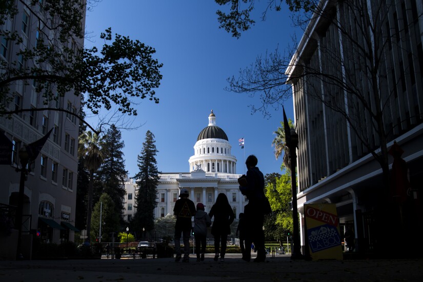 Pedestrians walk past the California State Capitol building in Sacramento, California, U.S.