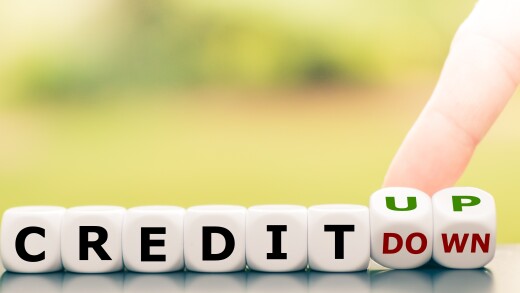 Hand turns dice and changes the expression "credit down" to "credit up".