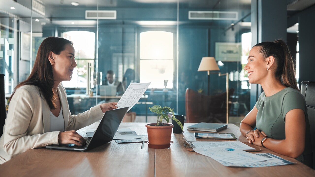 Two women discussing papers and graphs at conference room table