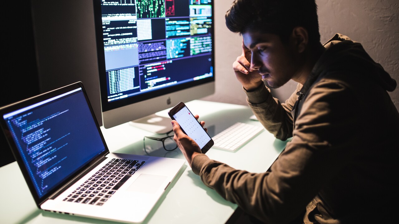 Man sitting at a desk staring at computer code.