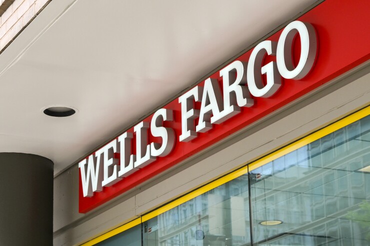 The Wells Fargo sign is in front of the bank; it's daytime.