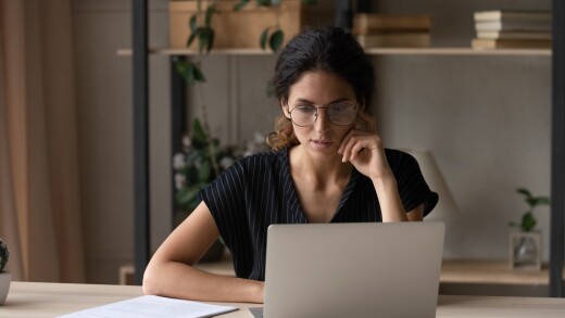 Close up thoughtful businesswoman in glasses looking at laptop screen