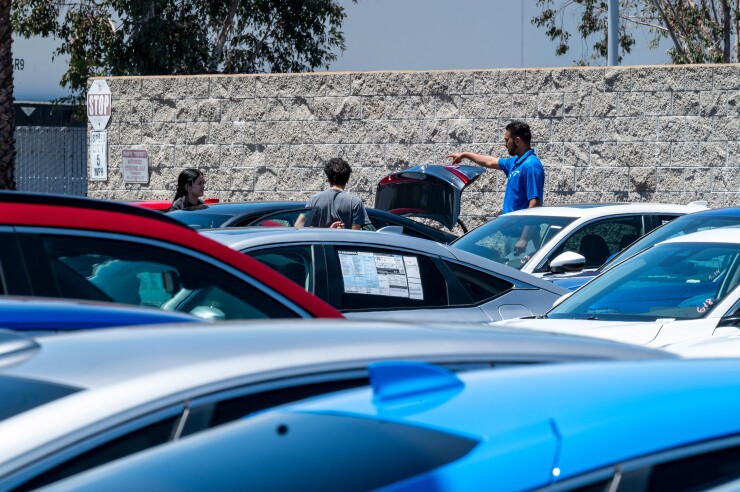 A car lot with three people looking at one car