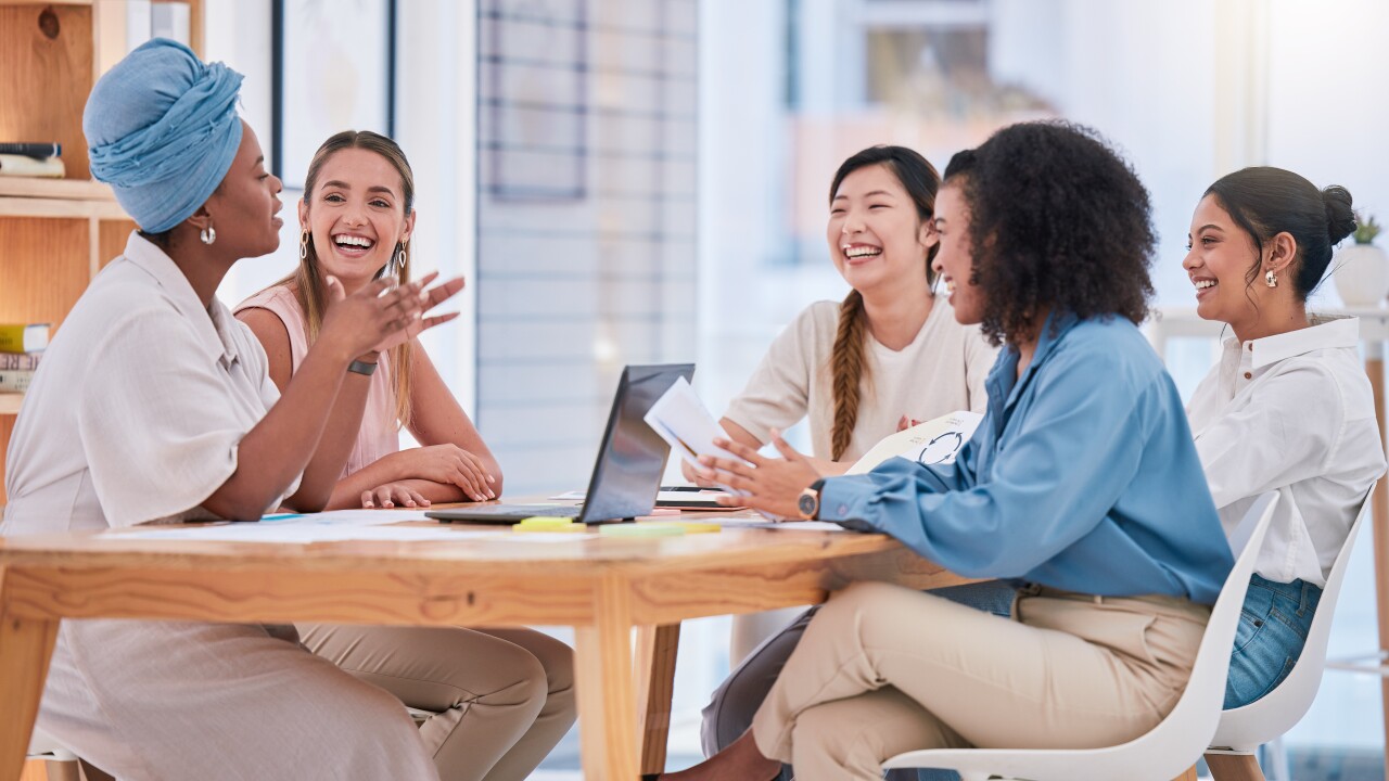 Group of women sitting at table in office working, talking