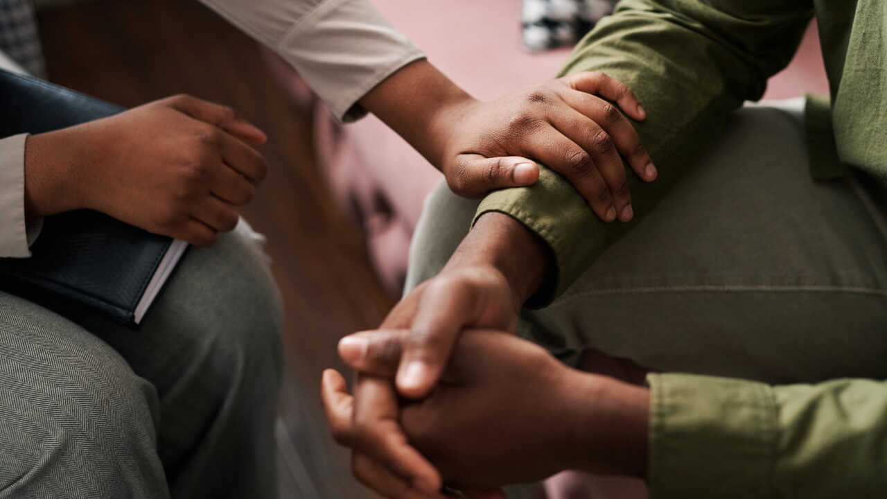 A person sitting down consoling another person.