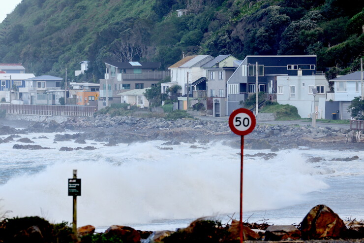 Waves on a beach with houses in the background.