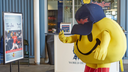 WooSox mascot Smiley aims a smartphone at an augmented reality target