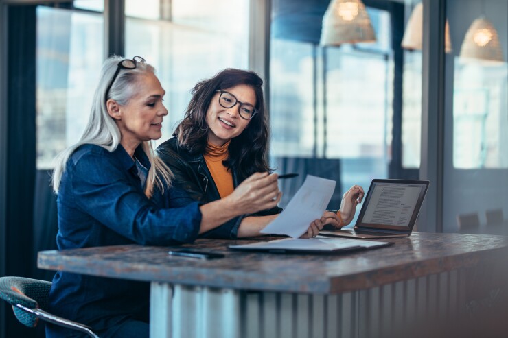 Two women discussing documents at the office.