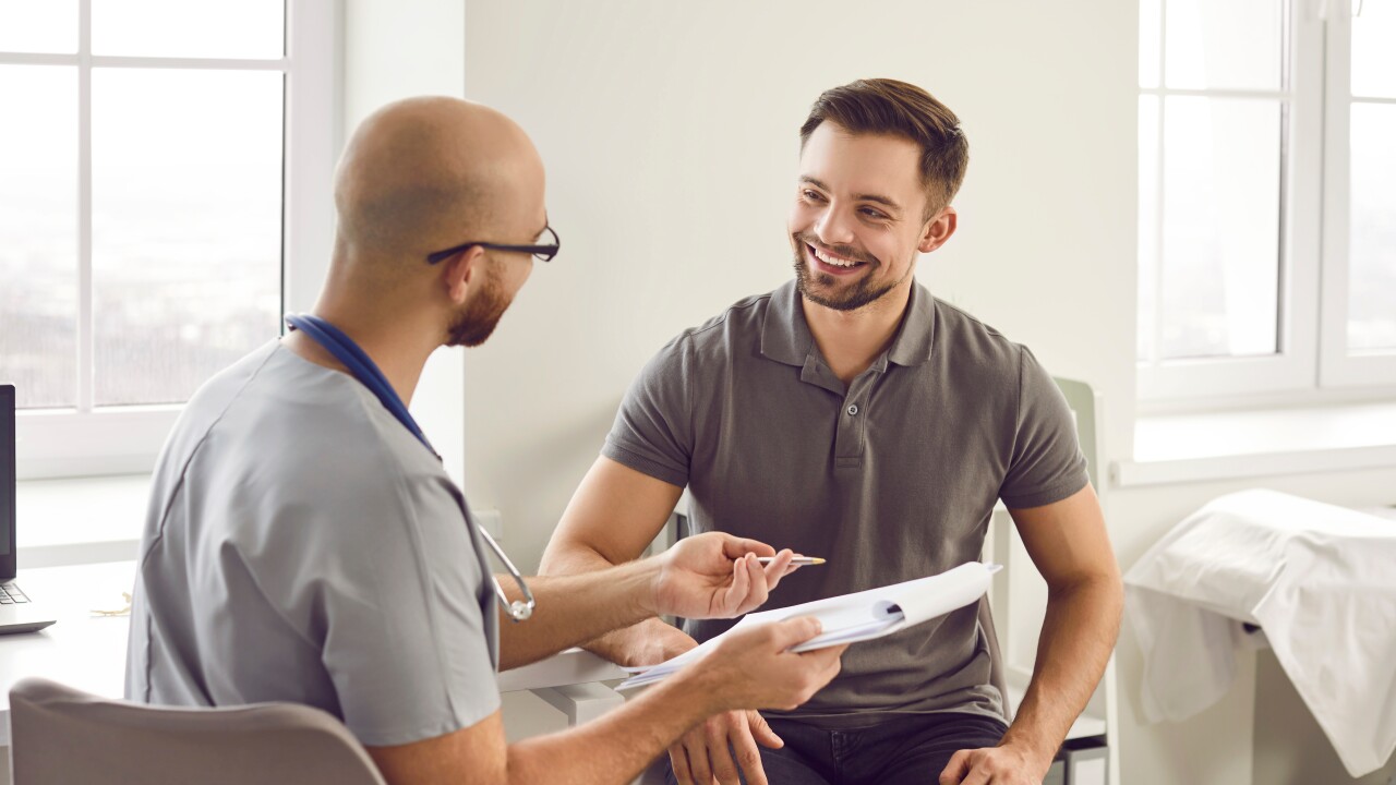 Man speaking with doctor, in doctor's office, smiling