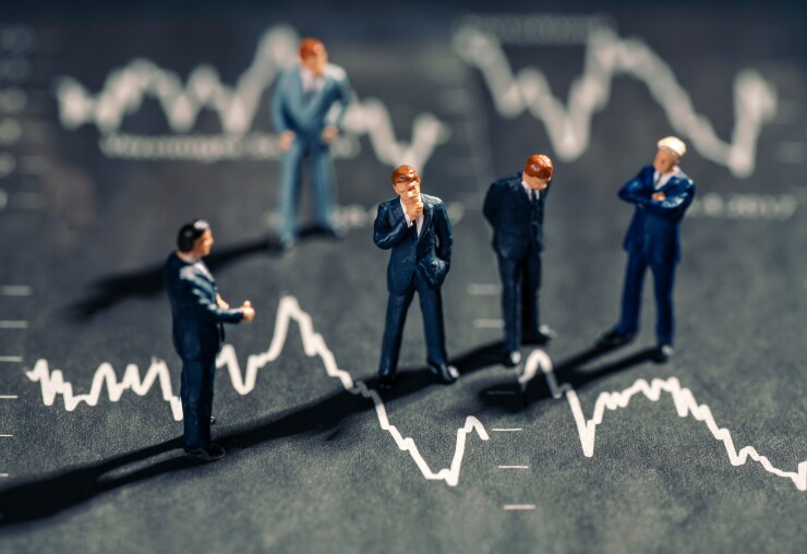 Mini figures of businessmen standing on top of a stock market chart