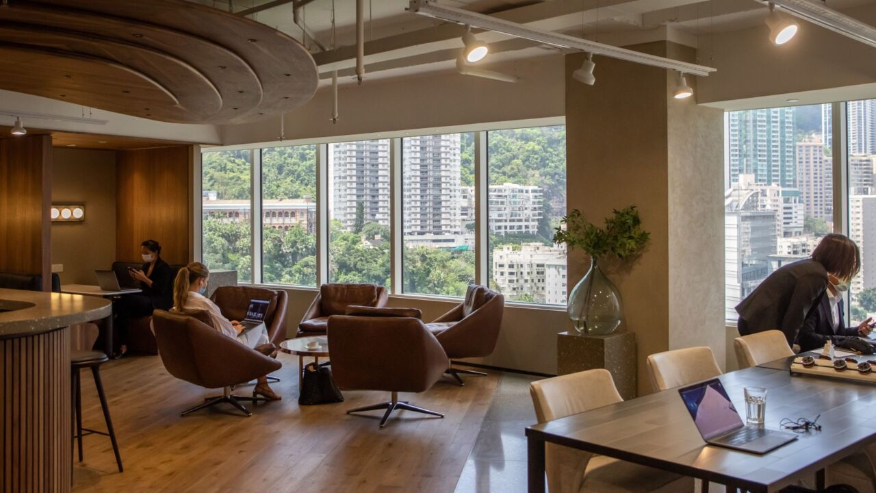 People wearing protective masks work in a shared workspace at the Executive Centre co-working office space in Hong Kong, China, on Thursday, April 16, 2020. Whether escaping tiny apartments that aren't conducive to work, or less concerned by a virus that has infected around 1,000 residents compared to more than 110,000 New Yorkers, the surprise result is co-working providers are thriving in Hong Kong, even as much of the world remains in lockdown. Photographer: Paul Yeung/Bloomberg