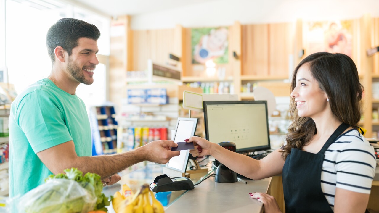 Man handing cashier credit card for groceries, paying