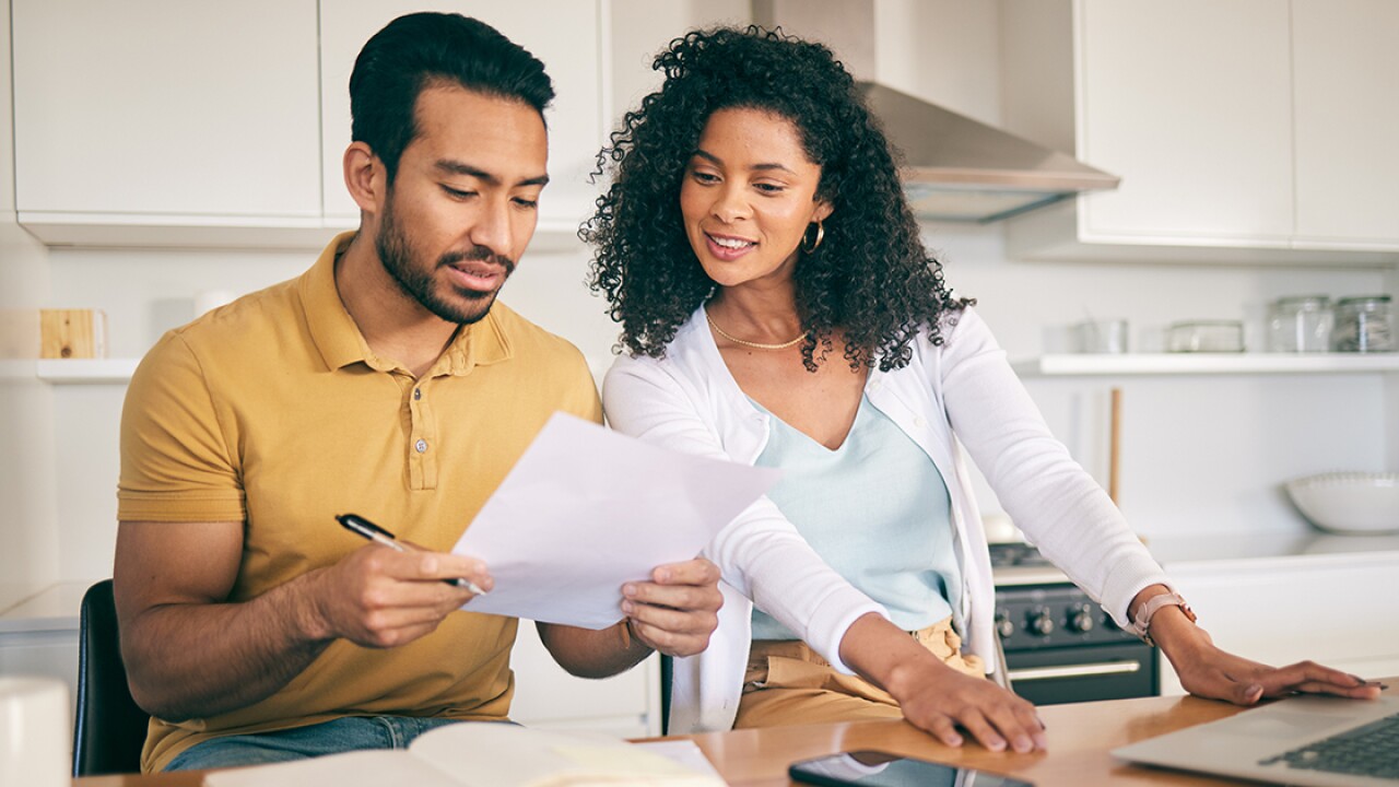 Couple looking at a paper in front of a computer.