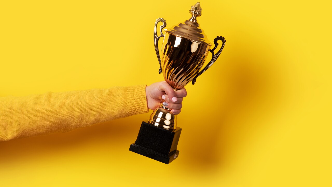 Woman holding a trophy against a yellow background