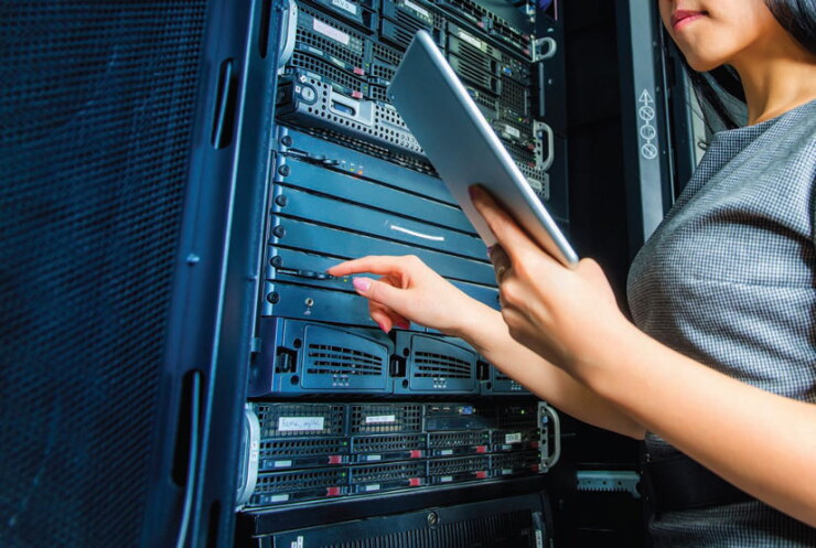 A person with a tablet doing work on a server.