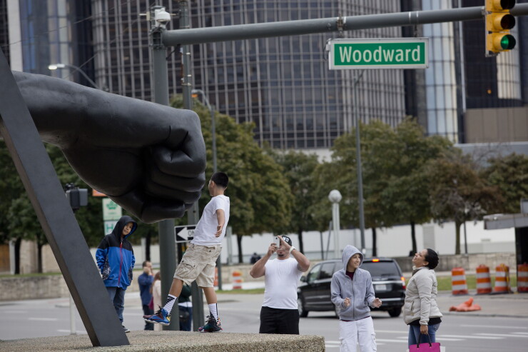 A man takes a photo of a boy in front of the the Monument to Joe Louis, also knows as "the fist", in downtown Detroit, Michigan, U.S., on Sunday, Oct. 4, 2015