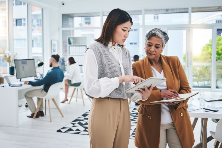 Two women standing together looking at an iPad