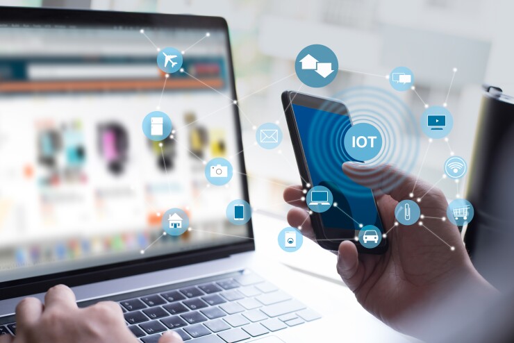 A person using a computer and a phone with an IOT graphic