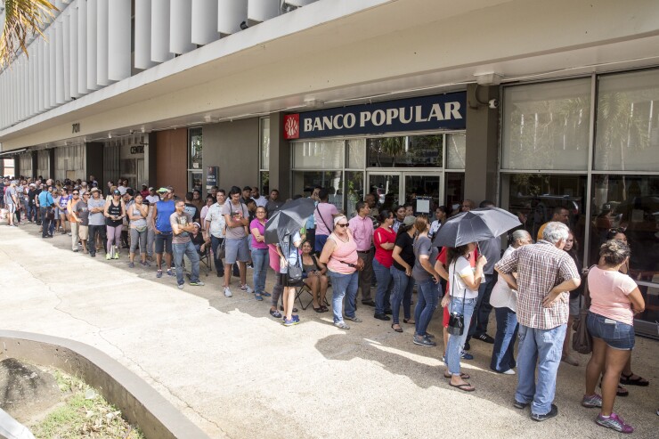 People stand in line to withdraw cash from a Banco Popular ATM after Hurricane Maria in San Juan, Puerto Rico.