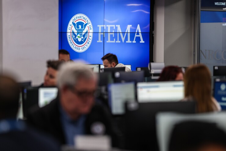 A FEMA sign and people working at the National Response Coordination Center in Washington.
