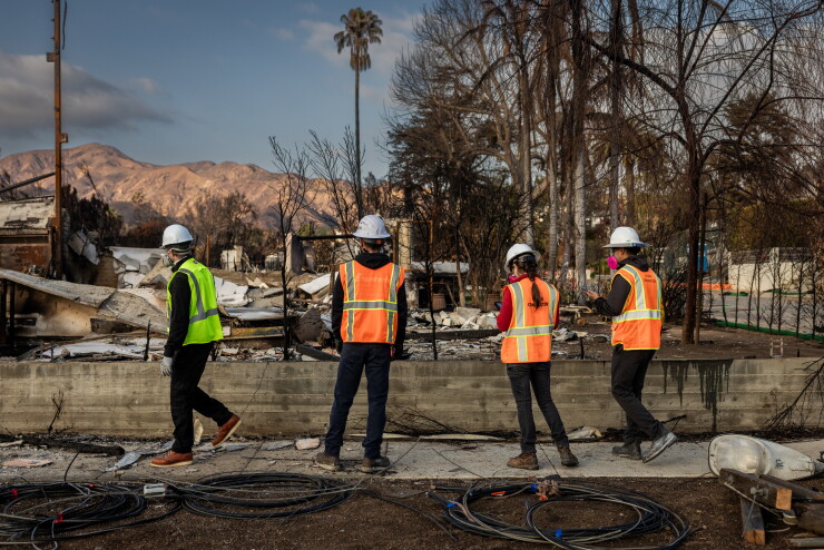 Workers examine homes after the Palisades Fire in the Pacific Palisades area of Los Angeles.