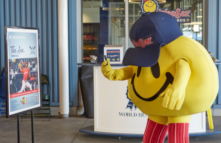 WooSox mascot Smiley aims a smartphone at an augmented reality target