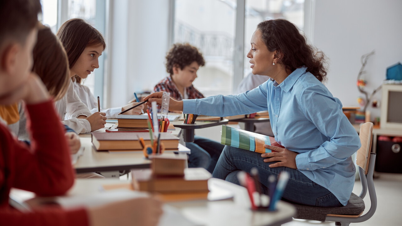 Teacher sitting with students, helping