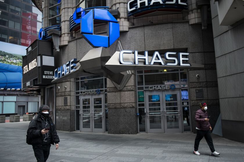 Pedestrians wearing protective masks walk past a JPMorgan Chase bank branch in New York on April 10, 2020.