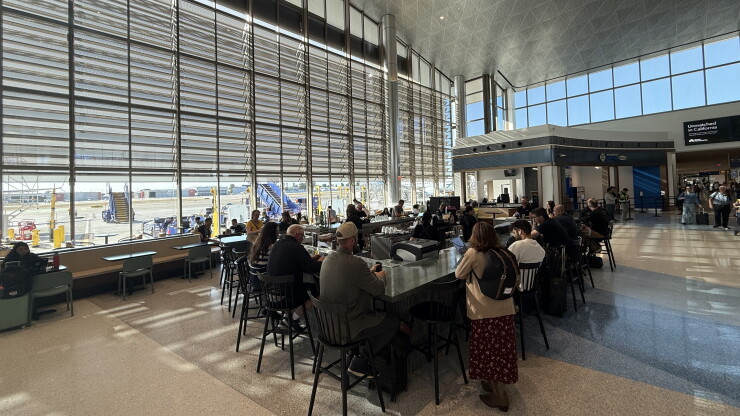 Passengers inside a high-ceiling naturally lit airport terminal