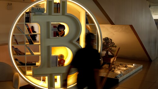 A picture of a large bookcase in the shape of the bitcoin B symbol.