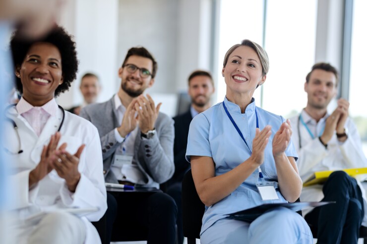 Medical professionals sitting in chairs clapping