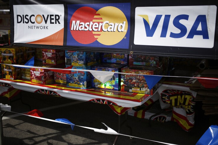 Visa, Mastercard, and Discover credit card signage is displayed at a fireworks stand.