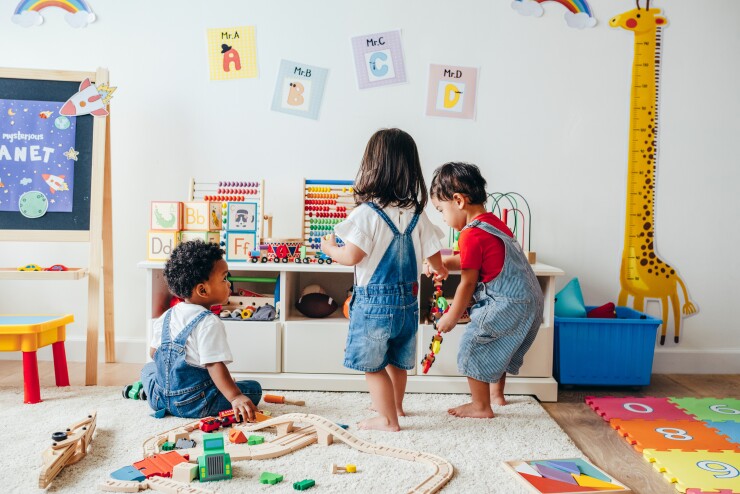 Three children play in a colorful playroom.