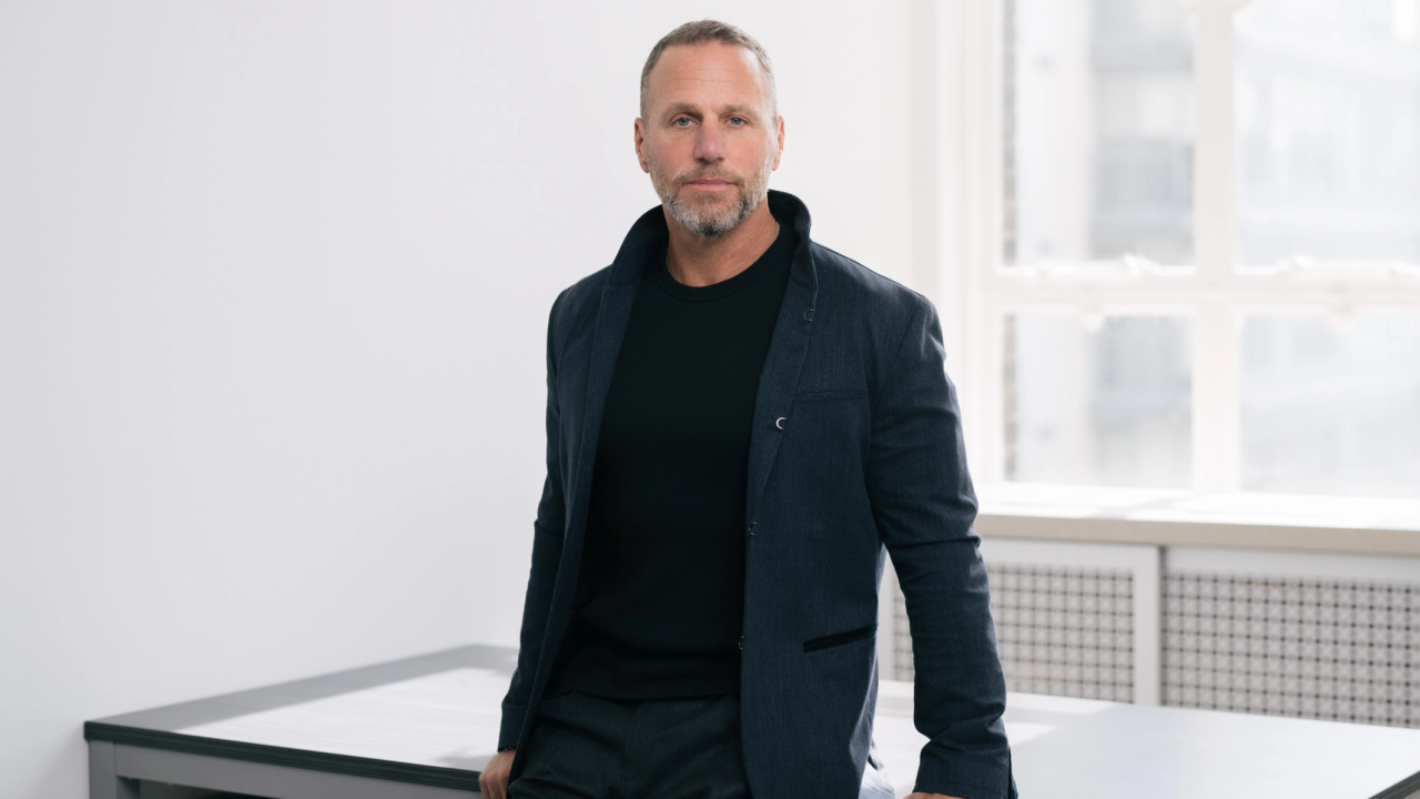 Propel Holdings CEO Clive Kinross leans against table in well-lit room for a headshot.