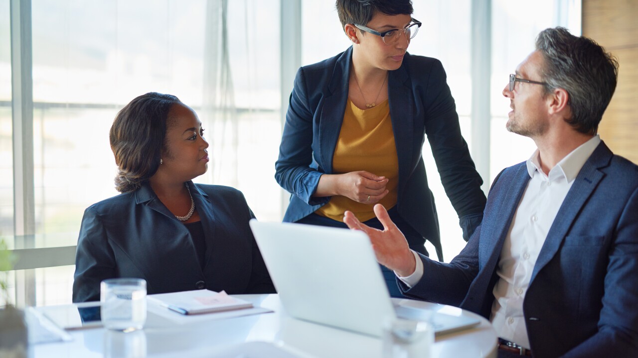 Managers in a work meeting sitting around a computer