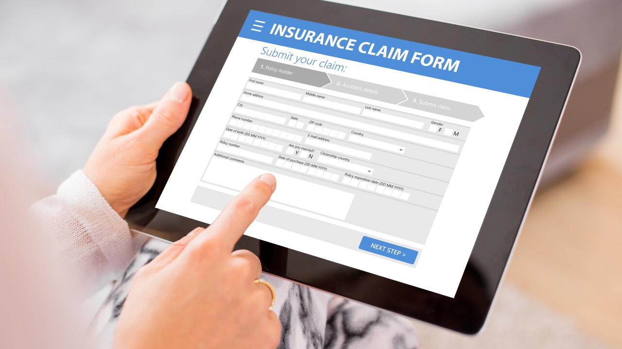 Hand holding tablet computer displaying an insurance claim form