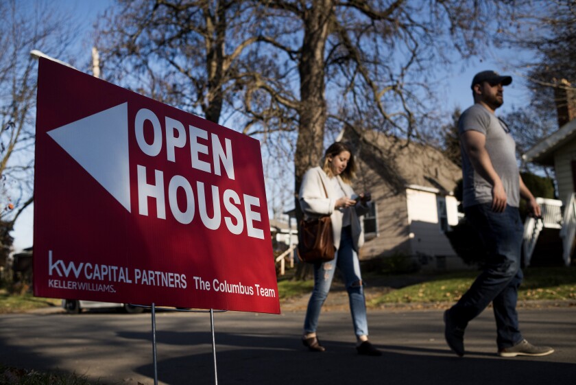 Potential home buyers walk past an "Open House" sign displayed in the front yard of a property for sale in Columbus, Ohio.