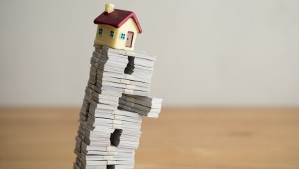 Model house on US dollar banknotes with white wall background copy space. Mortgage loan for buying home or real estate property, money risk management in financial, foreclosure and bankruptcy concept