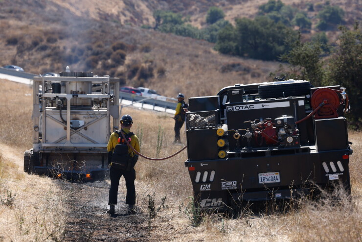 Technician operating BurnBot for prescribed burn demo on a hillside
