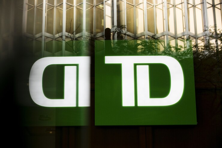 Toronto-Dominion Bank signage is reflected on a building in the financial district of Toronto.