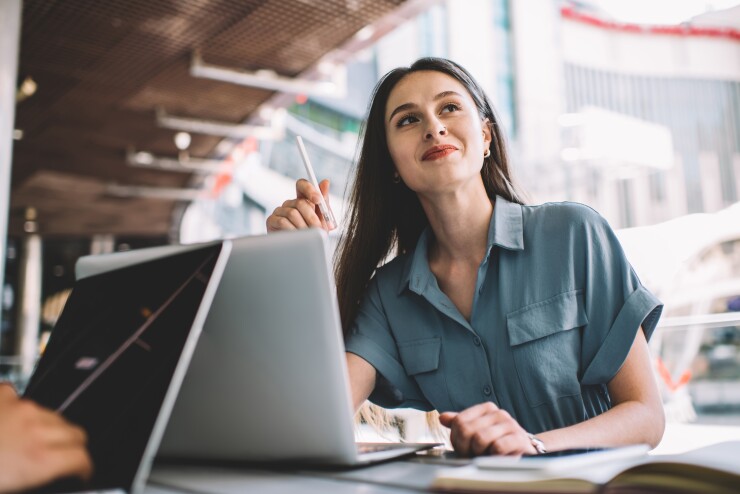 Millennial woman looking in the distance with a pen in her hand