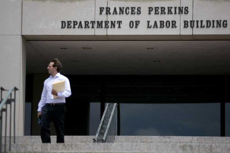 Department of Labor. man walks in front of building by Bloomberg News