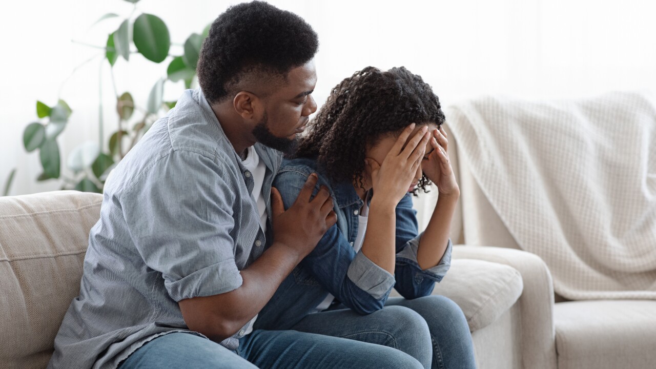 Man comforting a woman crying on the sofa.