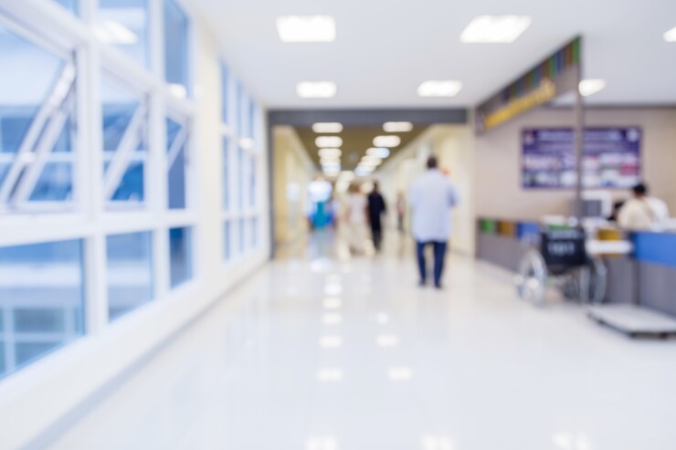 Blurred image of a hospital corridor with people walking down the hall