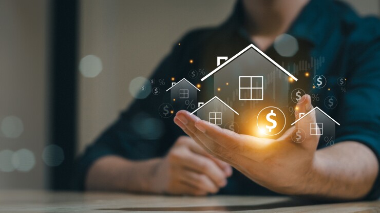Photo illustration with virtual homes and dollar signs held in man's hand.