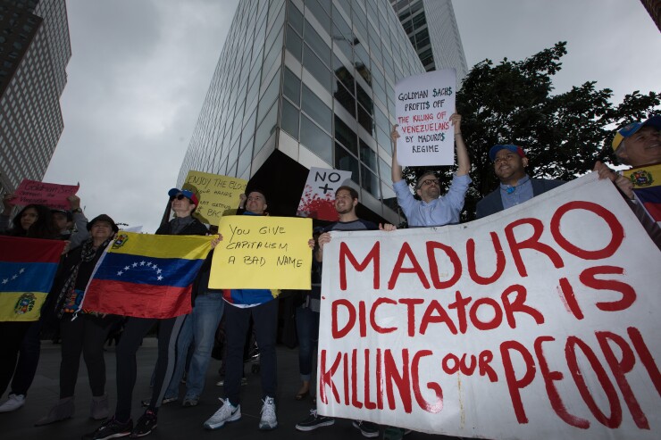 Demonstrators hold signs and Venezuelan flags during a protest outside of the Goldman Sachs headquarters in New York.