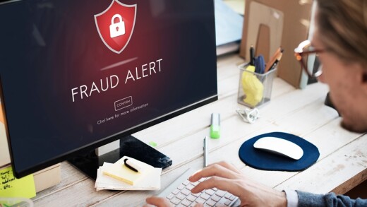 Fraud alert pops up on the computer screen in front of a man