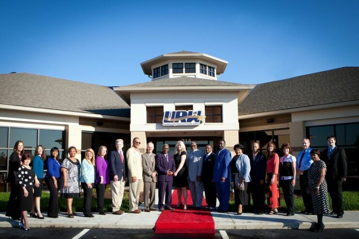 “Together We Make Family.” Senior leadership and employees at URW Community FCU pose outside headquarters.